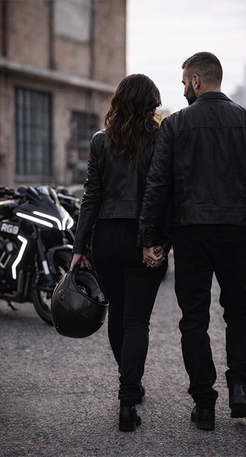 Couple marchant avec casque moto à la main devant motos RG Motorcycle, lifestyle motard moderne